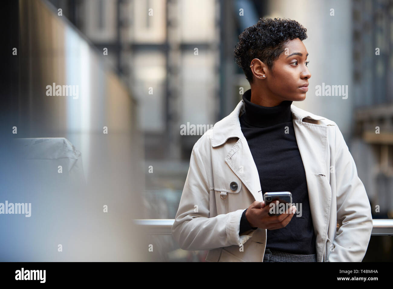 Junge schwarze Geschäftsfrau, die in der Stadt mit Smartphone in der Hand, Nahaufnahme, selektiver Fokus Stockfoto