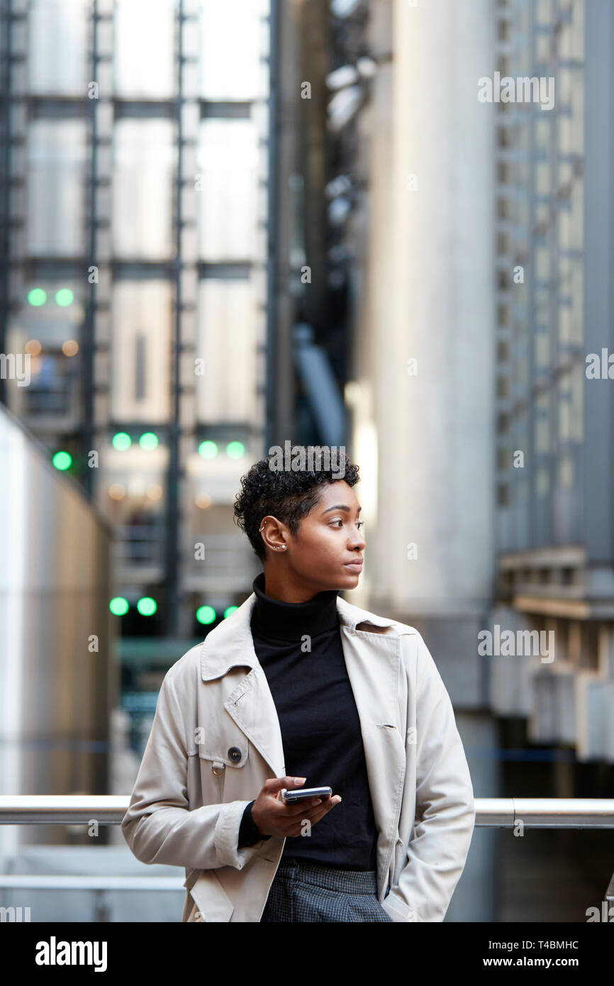 Junge schwarze Geschäftsfrau, die in der Stadt mit Smartphone in der Hand, Nahaufnahme, vertikal Stockfoto