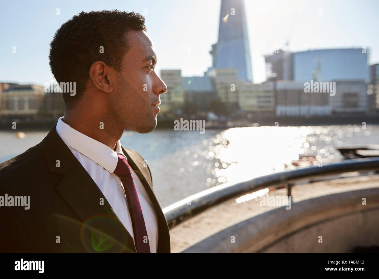 Junge schwarze Unternehmer tragen Hemd und Krawatte an der Themse, London, weg suchen, mit Hintergrundbeleuchtung Stockfoto