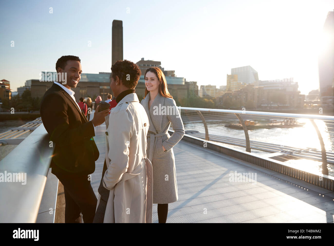 Drei tausendjährigen Kollegen stehen mit Millennium Bridge, wie die Sonne untergeht Stockfoto