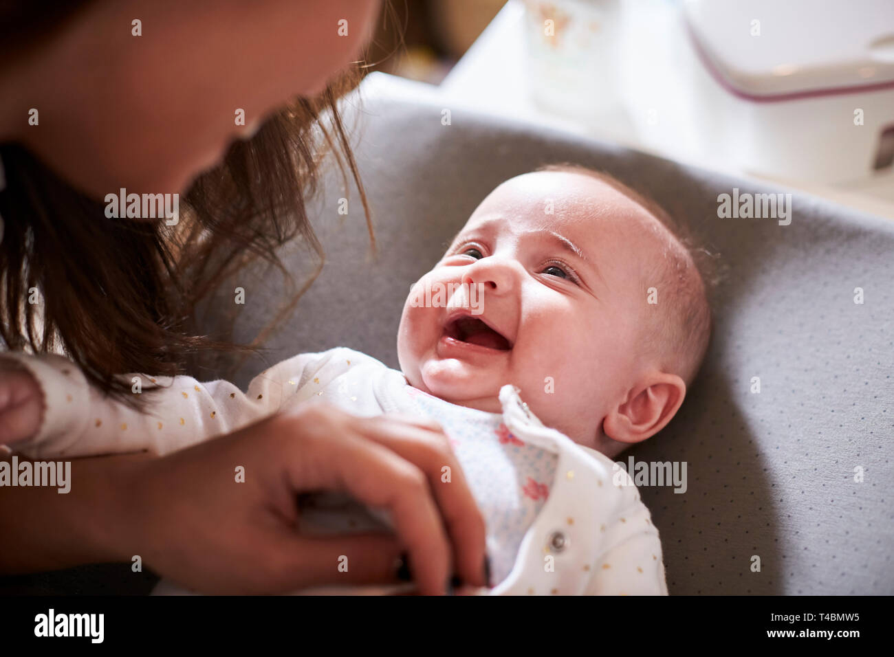 Gerne vier Monate alten Baby auf Wickeltisch bis an seine Mutter zu suchen, über die Schulter, Stockfoto