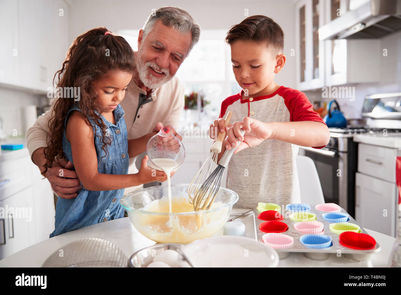 Bruder und Schwester am Küchentisch, Backmischung mit ihren Großvater, Nahaufnahme Stockfoto