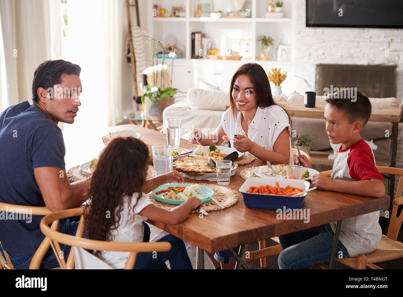 Junger spanischer Familie am Esstisch Abendessen essen zusammen zu sitzen Stockfoto