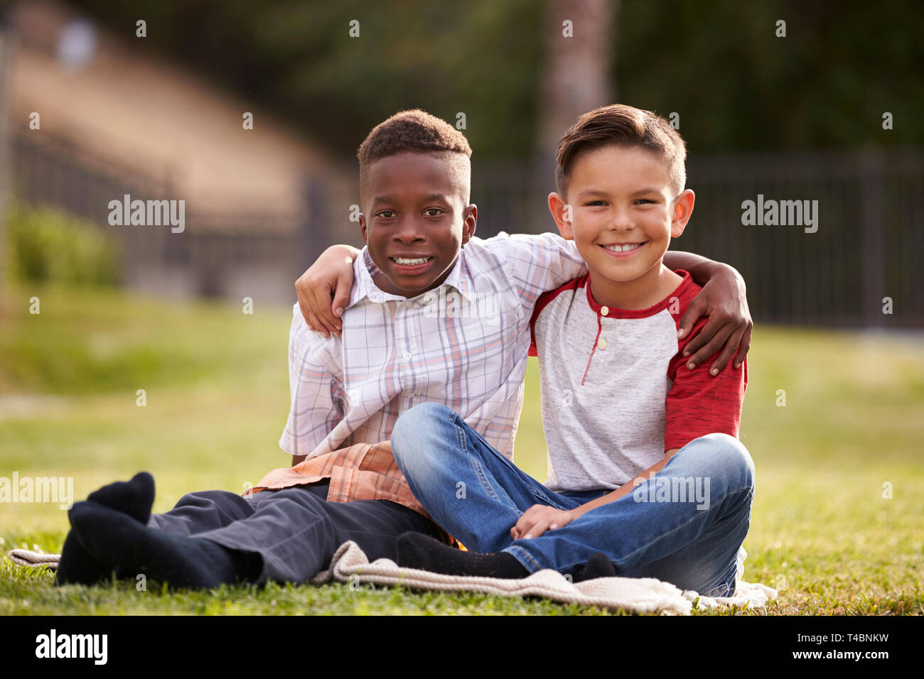 Zwei vor - jugendlich männliche Freunde sitzen auf der Wiese im Park, Arme um miteinander, mit Kamera suchen Stockfoto