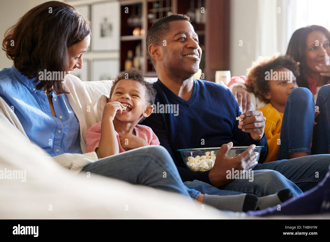 Drei generation Familie Familie sitzt auf dem Sofa im Wohnzimmer, Fernsehen und essen Popcorn, selektiven Fokus Stockfoto