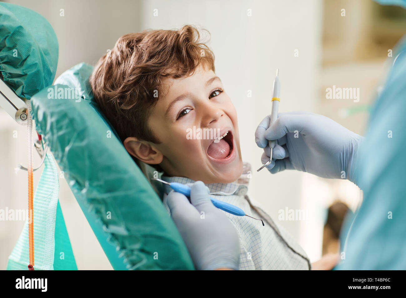 Kind lächelnd, während im Zahnarztstuhl sitzen. Stockfoto