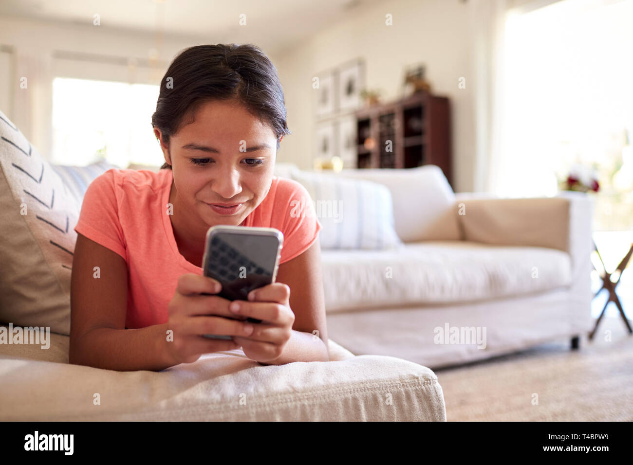 Teenager auf dem Sofa zu Hause im Wohnzimmer mit Smartphone, Nahaufnahme, niedrigen Winkel, in der Nähe Stockfoto
