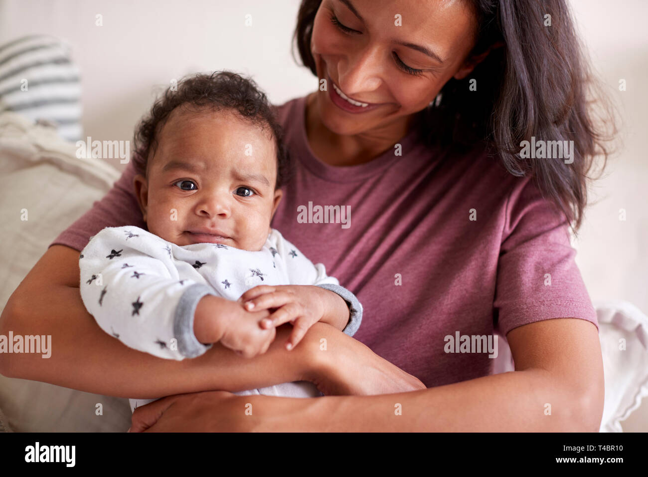 Nahaufnahme von gemischten Rennen junge junge Erwachsene Mutter ihr Baby boy Holding in ihren Armen, wie er blickt in die Kamera Stockfoto