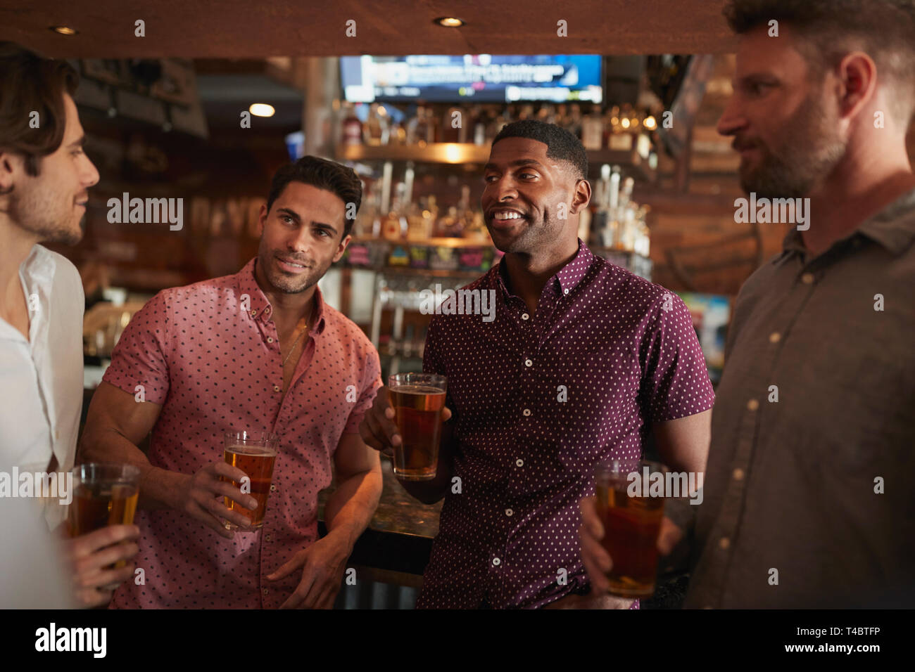 Gruppe von männlichen Freunden am Abend trinken Bier in der Bar zusammen Stockfoto