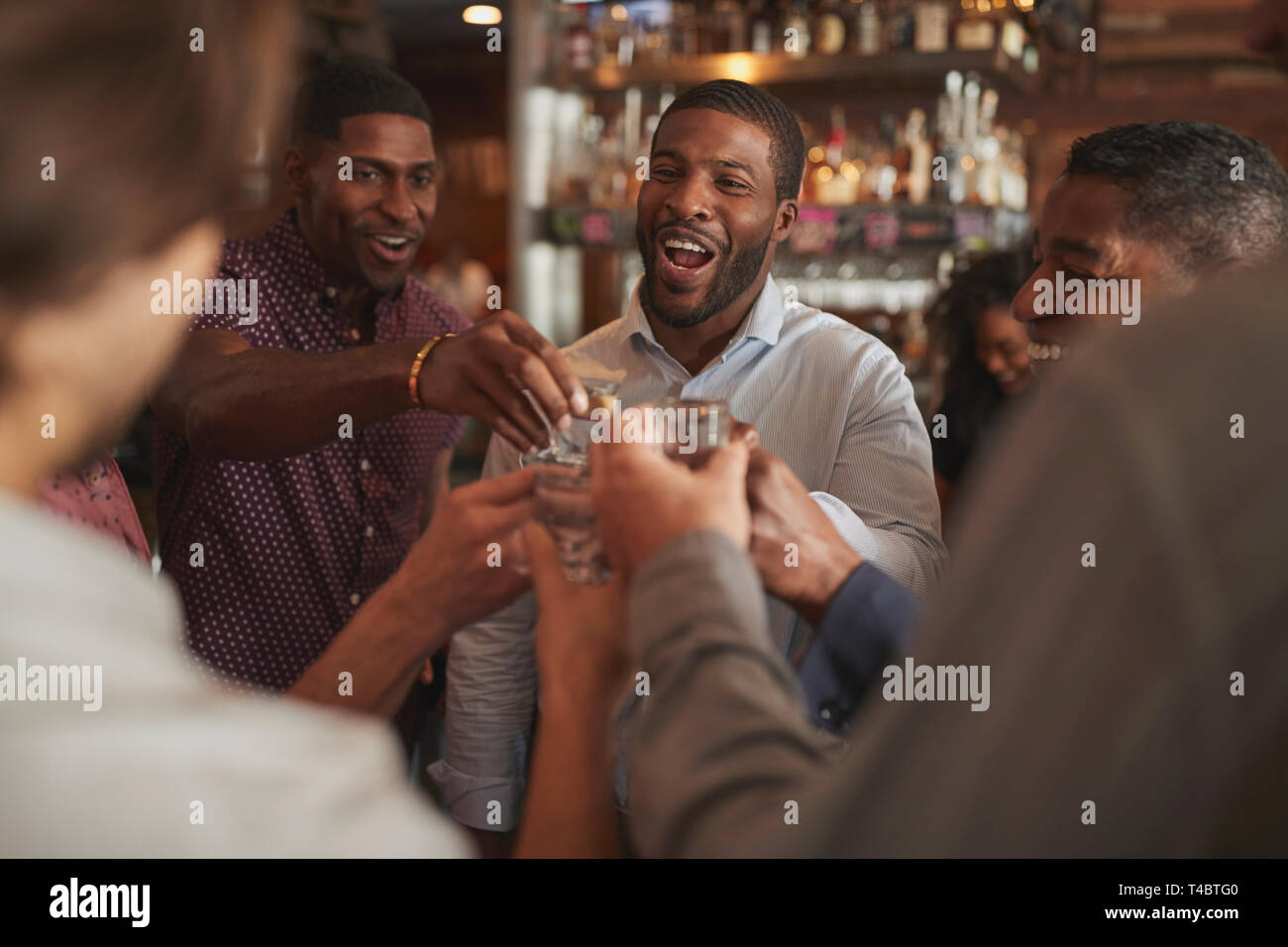 Gruppe von männlichen Freunden am Abend trinken Schüsse in Bar zusammen Stockfoto