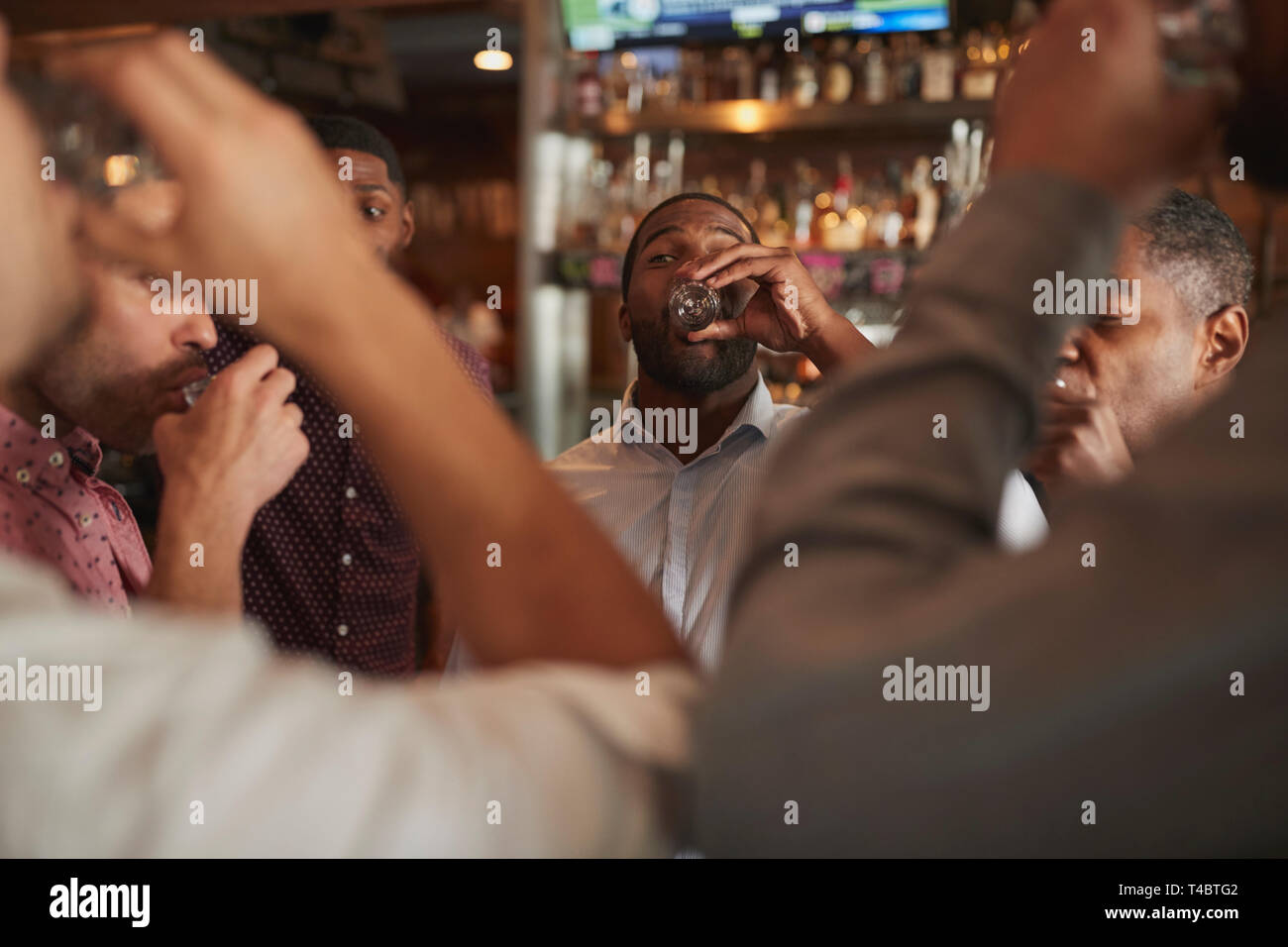 Gruppe von männlichen Freunden am Abend trinken Schüsse in Bar zusammen Stockfoto