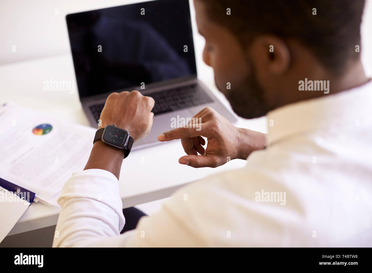 Unternehmer Arbeiten am Notebook am Schreibtisch in modernen Büro Daten auf Smart Watch Stockfoto