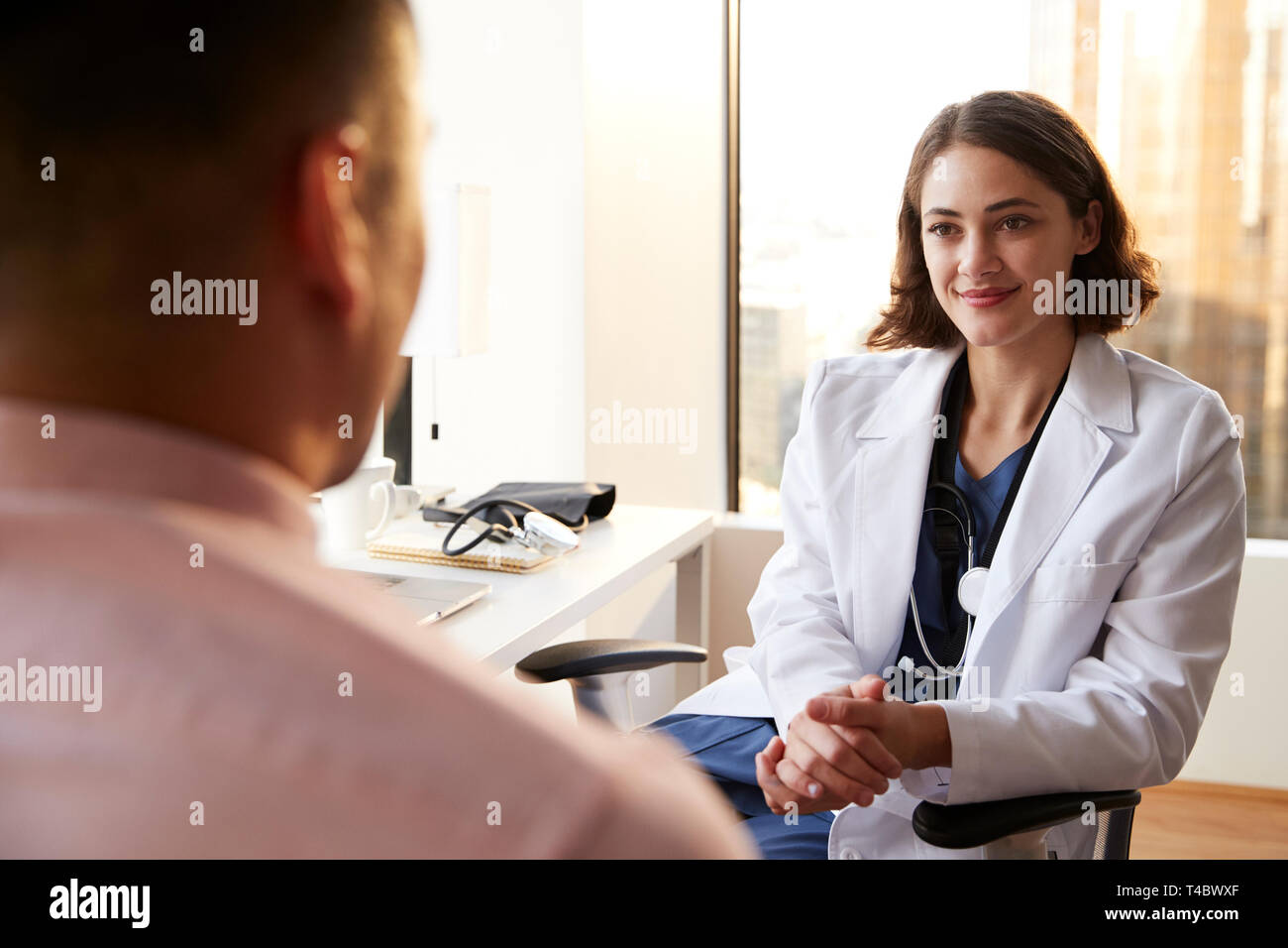 Blick über die Schulter des Mannes in Absprache mit Frau Doktor im Krankenhaus Büro Stockfoto
