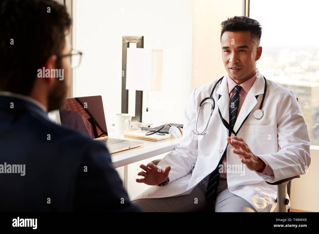 Blick über die Schulter des Mannes in Absprache mit männlicher Arzt im Krankenhaus Büro Stockfoto