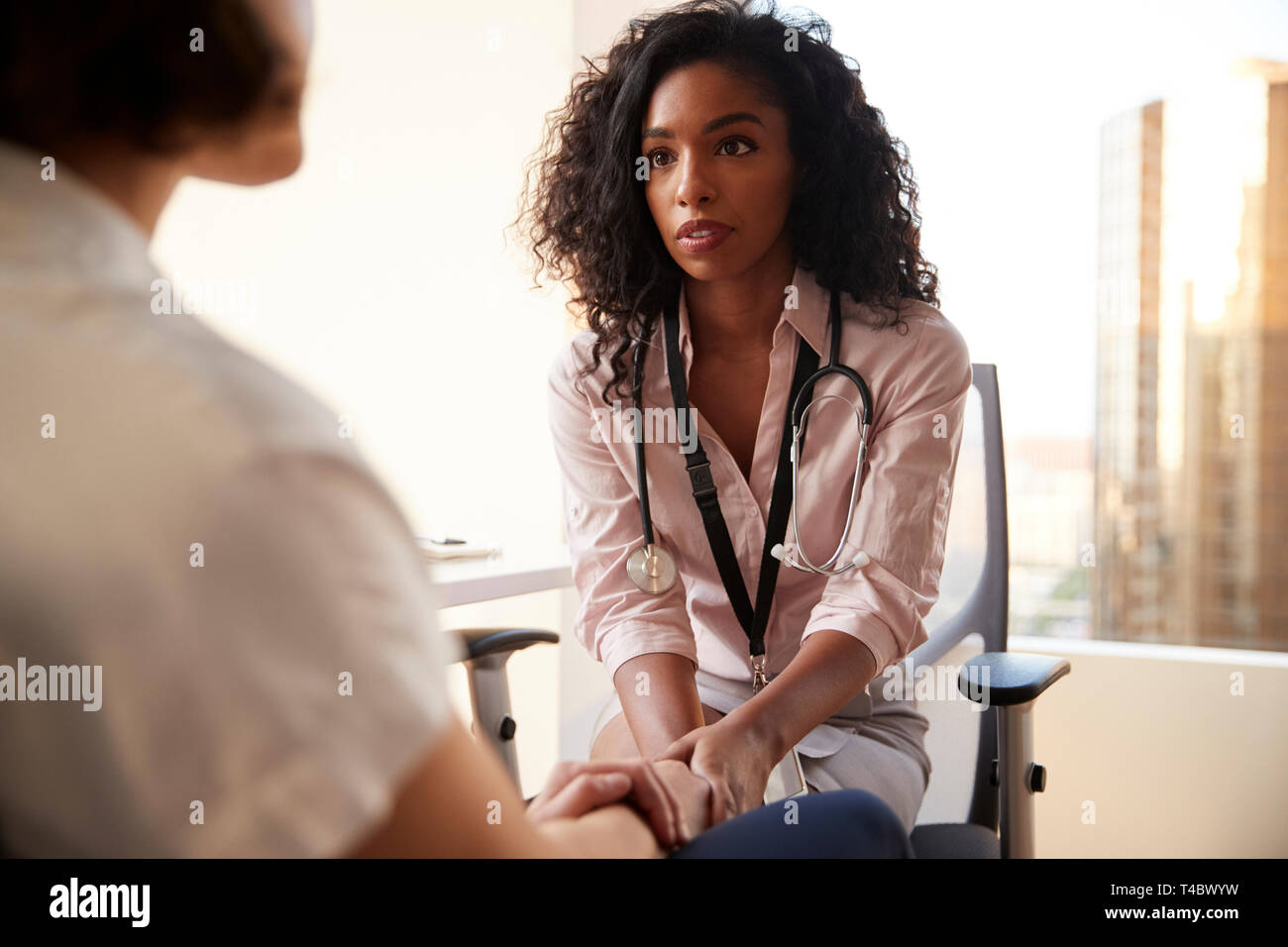 Ärztin im Amt beruhigend Patientin und halten Ihre Hände Stockfoto