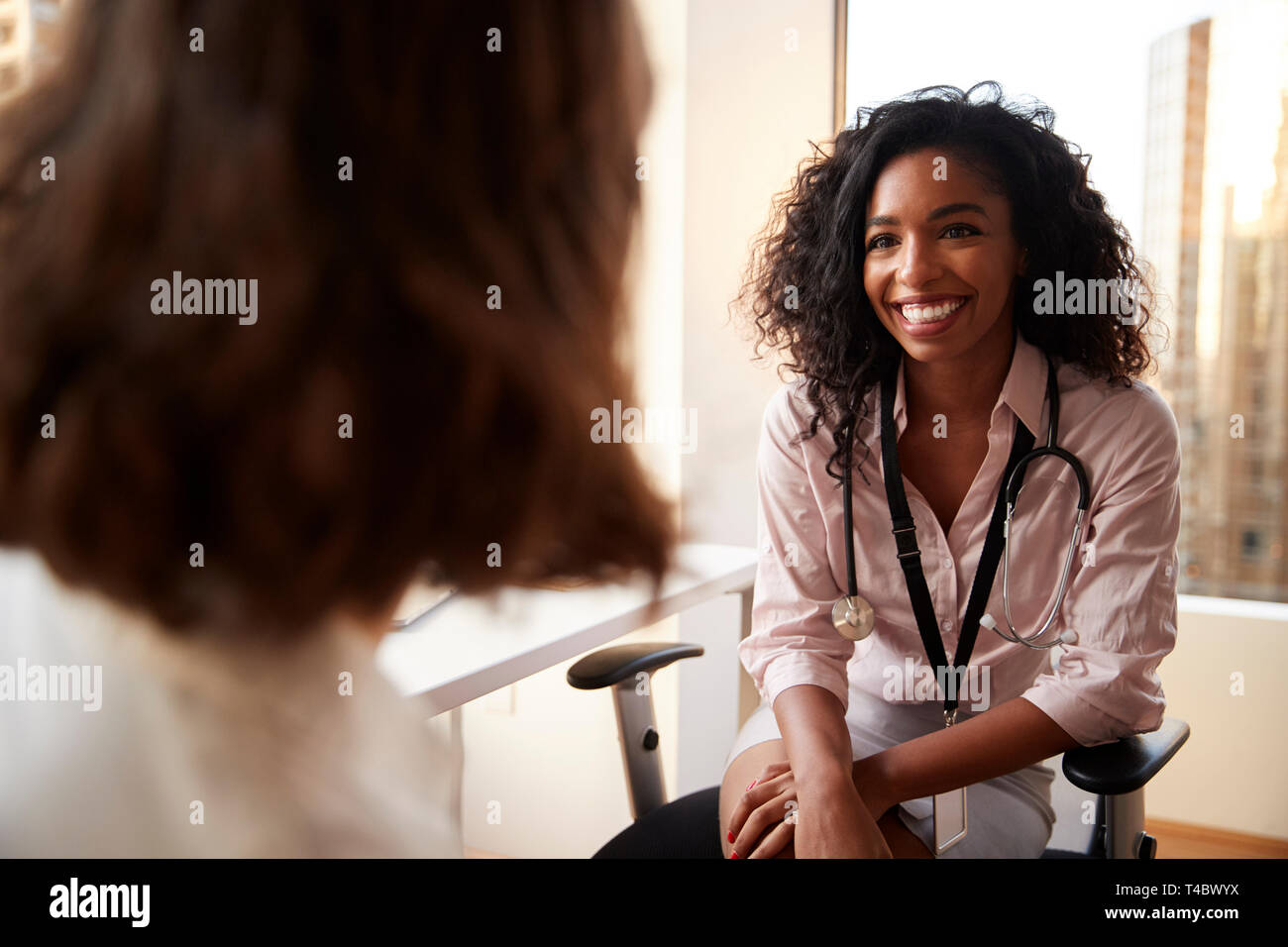 Blick über die Schulter der Frau in Absprache mit Frau Doktor im Krankenhaus Büro Stockfoto