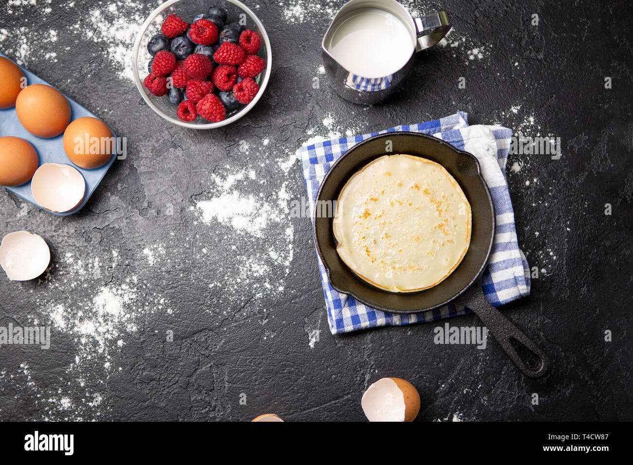 Foto oben auf Eier, Milch, Mehl, Beeren auf Schwarz. Stockfoto