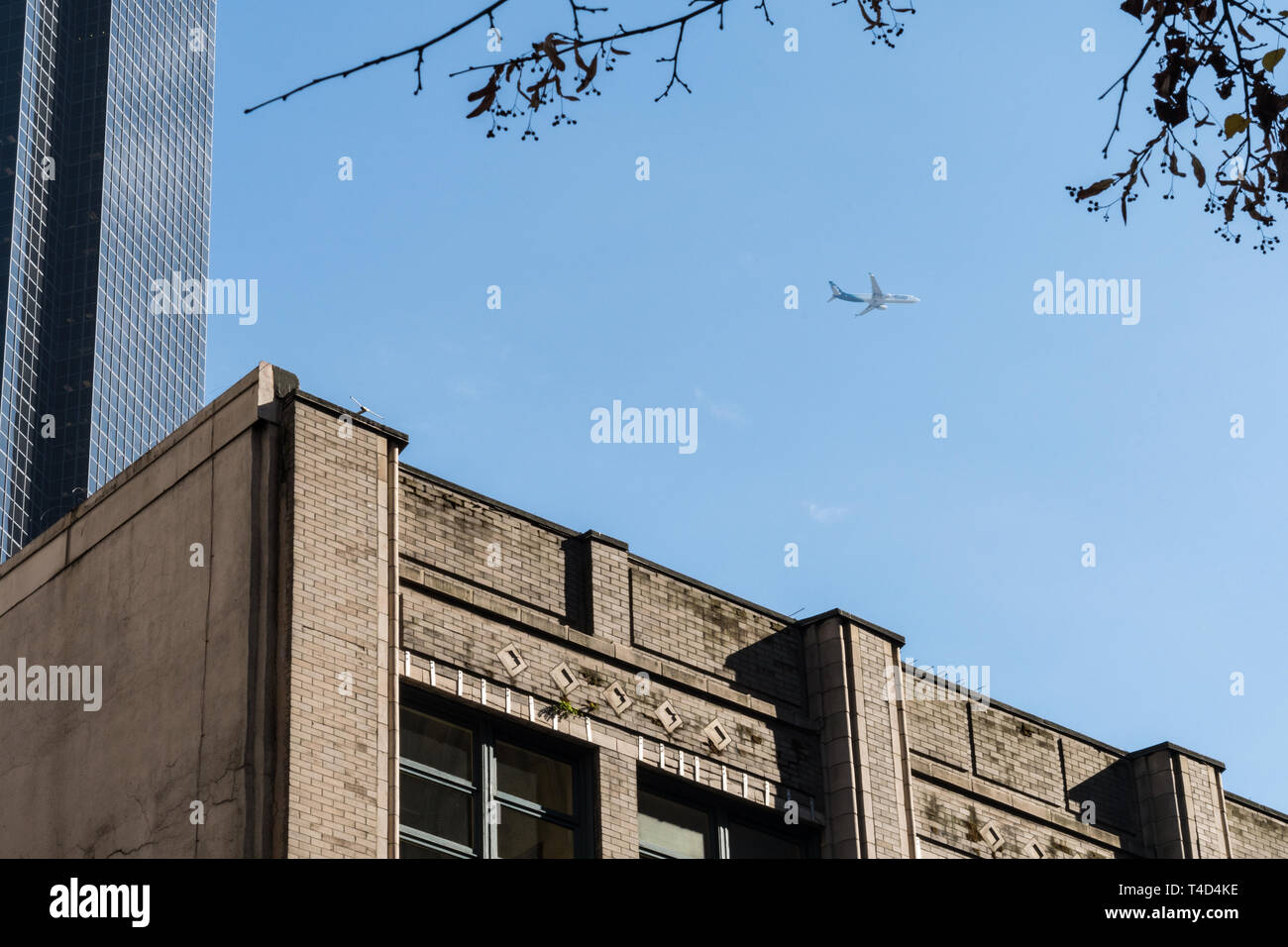 Kommerzielle Flugzeug fliegen über Downtown Seattle zwischen ein paar Wolkenkratzer gesehen. Stockfoto