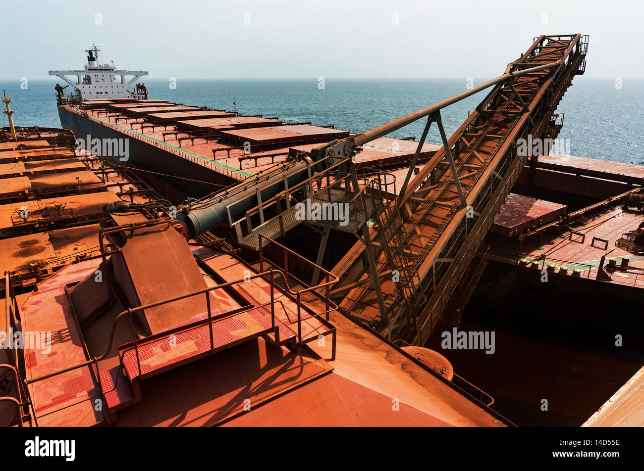 Port Operations für den Transport von Eisenerz. Entladen von Geldbußen Erz aus TGV transhipper Boot in Halten der OGV Ozean Schiff auf See Stockfoto