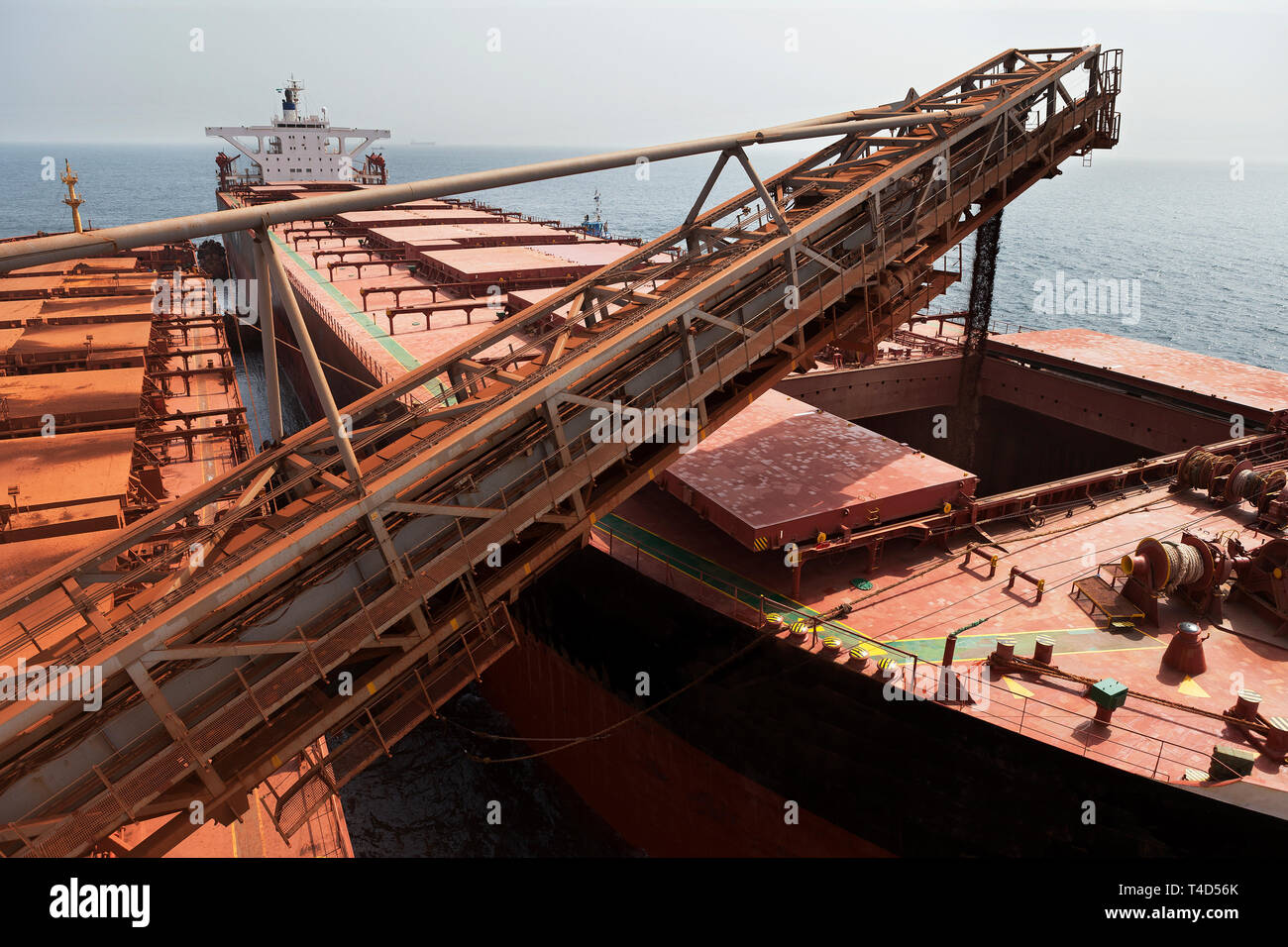 Port Operations für den Transport von Eisenerz. Entladen von Geldbußen Erz aus TGV transhipper Boot in Halten der OGV Ozean Schiff auf See Stockfoto