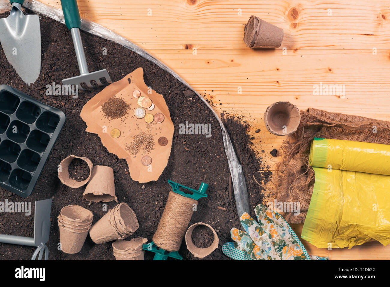 Preiswerte organische Nahrungsmittelproduktion und Gartengeräte, Ansicht von oben von Werkzeugen und Saatgut auf hölzernen Tisch im Garten mit einigen Euro-münzen als Konzept der l Stockfoto