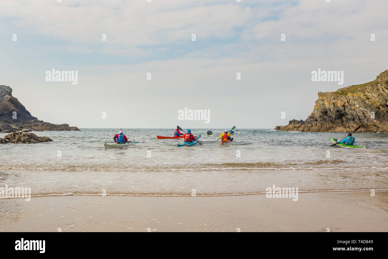 Blick aus der Nähe auf eine Gruppe von Menschen, die am britischen Strand Kajak fahren und ins Meer paddeln. Aufenthalt in Großbritannien. Stockfoto