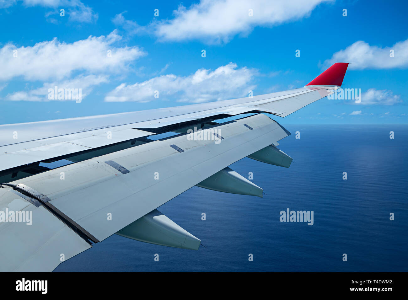 Flügel eines Flugzeugs aero Ebene mit Landeklappen auf blauen bewölkten Himmel Stockfoto
