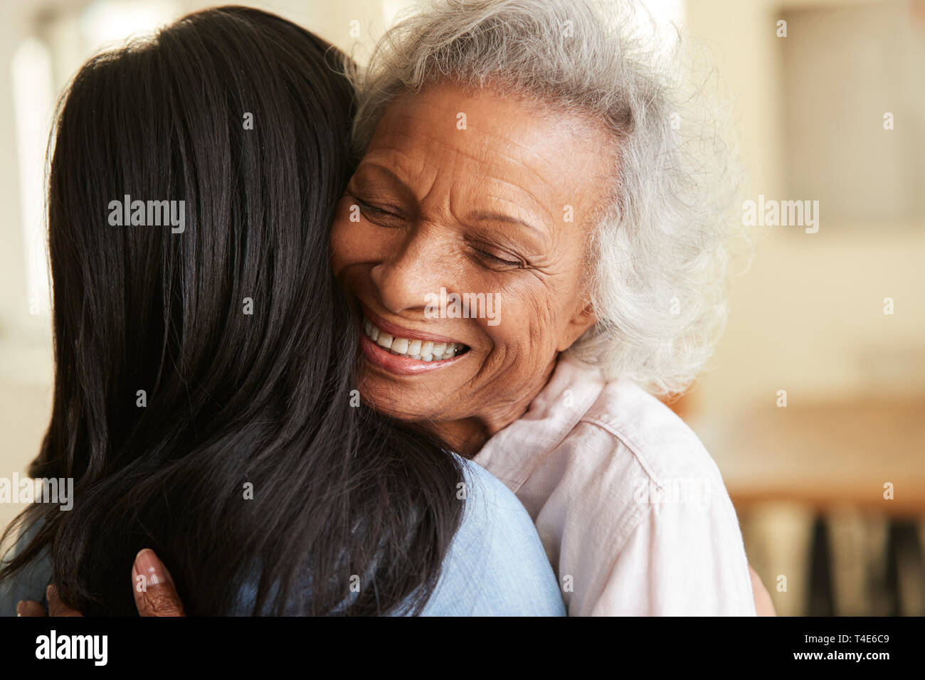 Blick über die Schulter des älteren Mutter umarmte von erwachsenen Tochter zu Hause Stockfoto
