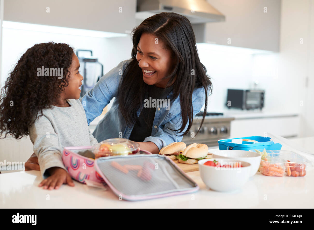 Tochter in der Küche zu Hause helfen Mutter gesund Lunchpaket zu machen Stockfoto
