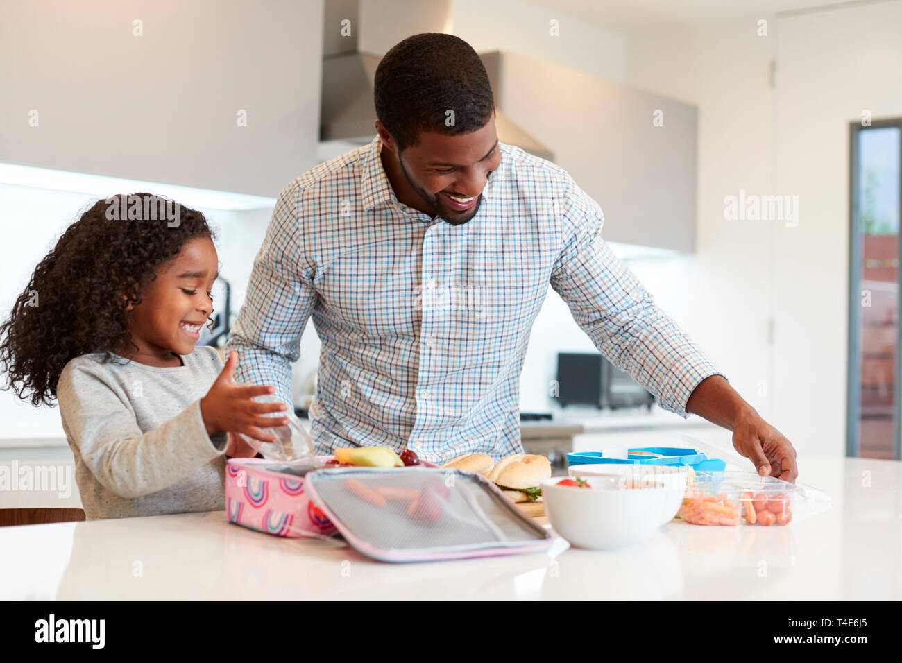 Tochter in der Küche zu Hause helfen Vater gesundes Lunchpaket zu machen Stockfoto