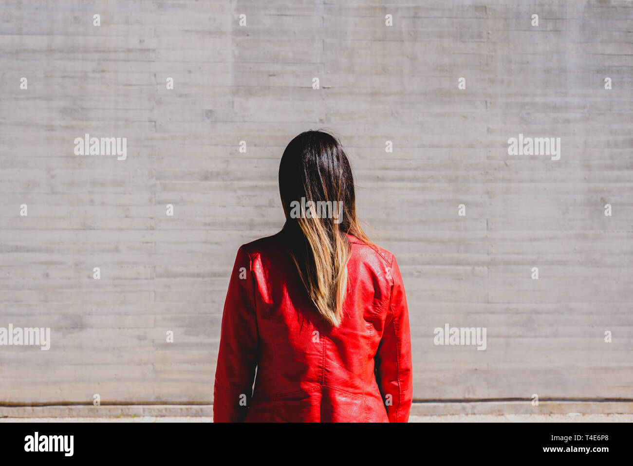 Hübsche, junge Frau mit glatten und dünnes Haar, mit dem Rücken zur Kamera und traurigen Geste, neutral grau Friedhof Hintergrund mit kopieren. Stockfoto