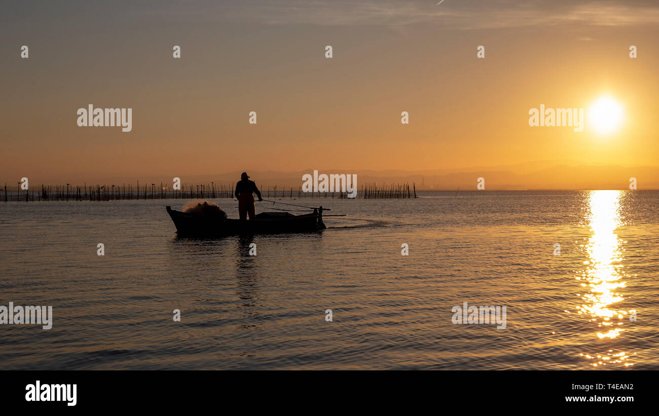 Mann in einem Boot bei Sonnenuntergang im Albufera Valencia, Valencia, Spanien. Stockfoto