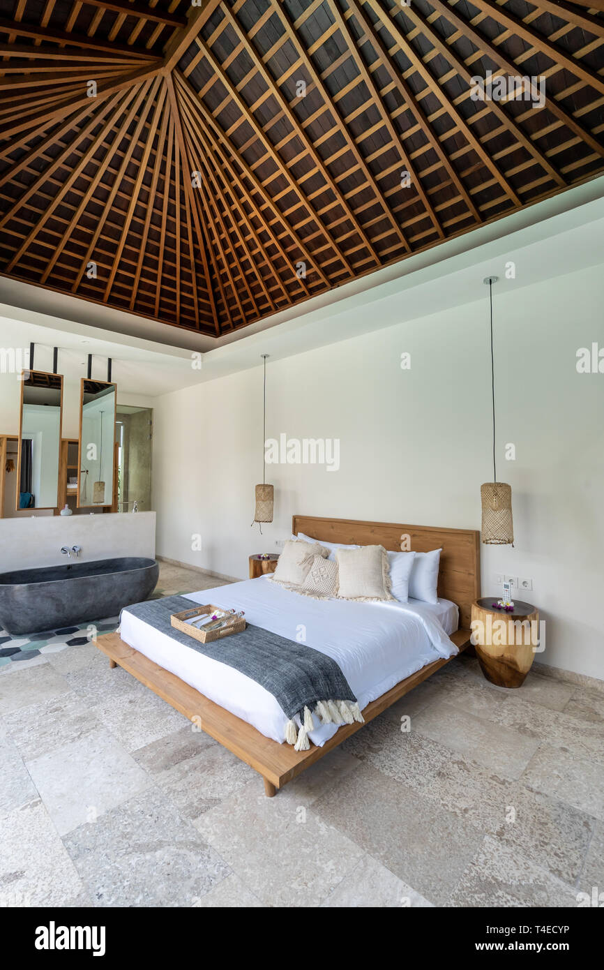 Ein gemütliches und luxuriöses Bett in einer Villa mit schönen Home  Interior in Kuta auf der Insel Lombok, Indonesien und einer Badewanne aus  Stein Stockfotografie - Alamy