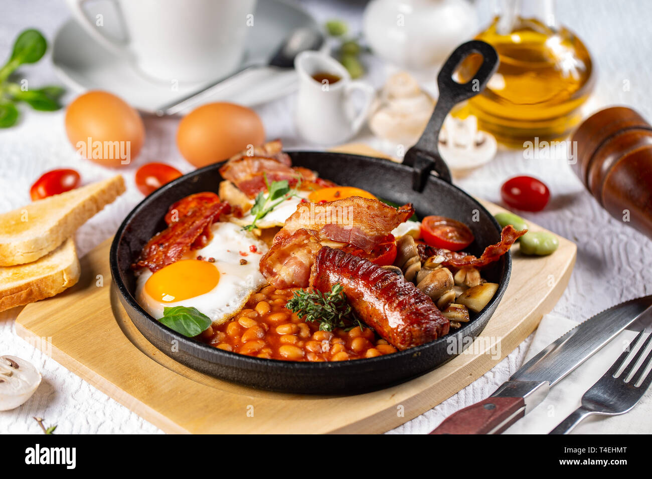 Traditionelles Englisches Frühstück mit Spiegelei, Würstchen, Bohnen, Pilze, gegrillten Tomaten und Speck Stockfoto