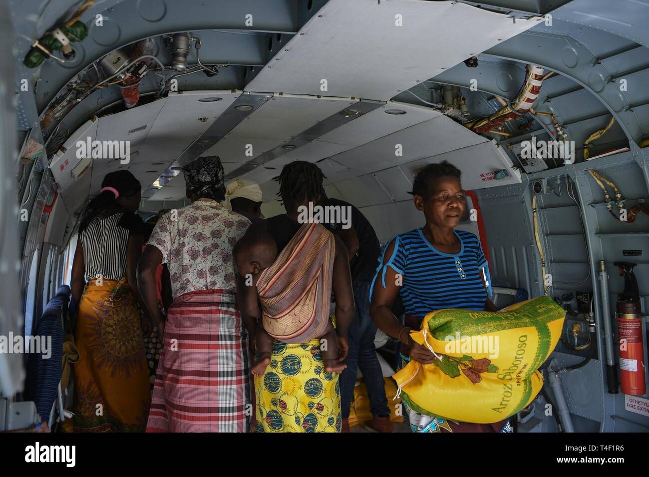 Lokale Frauen Hilfe Humanitäre Hilfe vom Welternährungsprogramm Hubschrauber in Bebedo, Mosambik, April 8, 2019 zu entlasten, bei humanitären Hilfsaktionen in der Republik Mosambik und der umliegenden Gebiete nach dem Zyklon Idai. Mannschaften von Combined Joint Task Force-Horn in Afrika, die führenden US-amerikanischen Verteidigungsministerium unterstützt Hilfsmaßnahmen in Mosambik, begann der unmittelbaren Vorbereitung zu reagieren nach einem Aufruf zur Unterstützung der US-Agentur für Internationale Entwicklung Katastrophenhilfe Response Team. Stockfoto