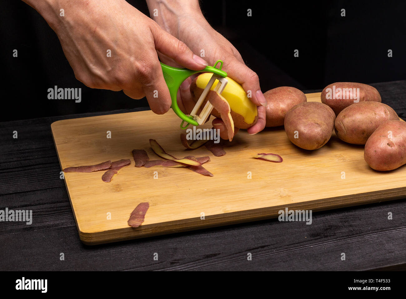 Der Prozess der Reinigung der Kartoffeln mit einem speziellen Messer, Schäler. Der Küchenchef bereitet Kartoffeln zum Braten oder Kochen Stockfoto