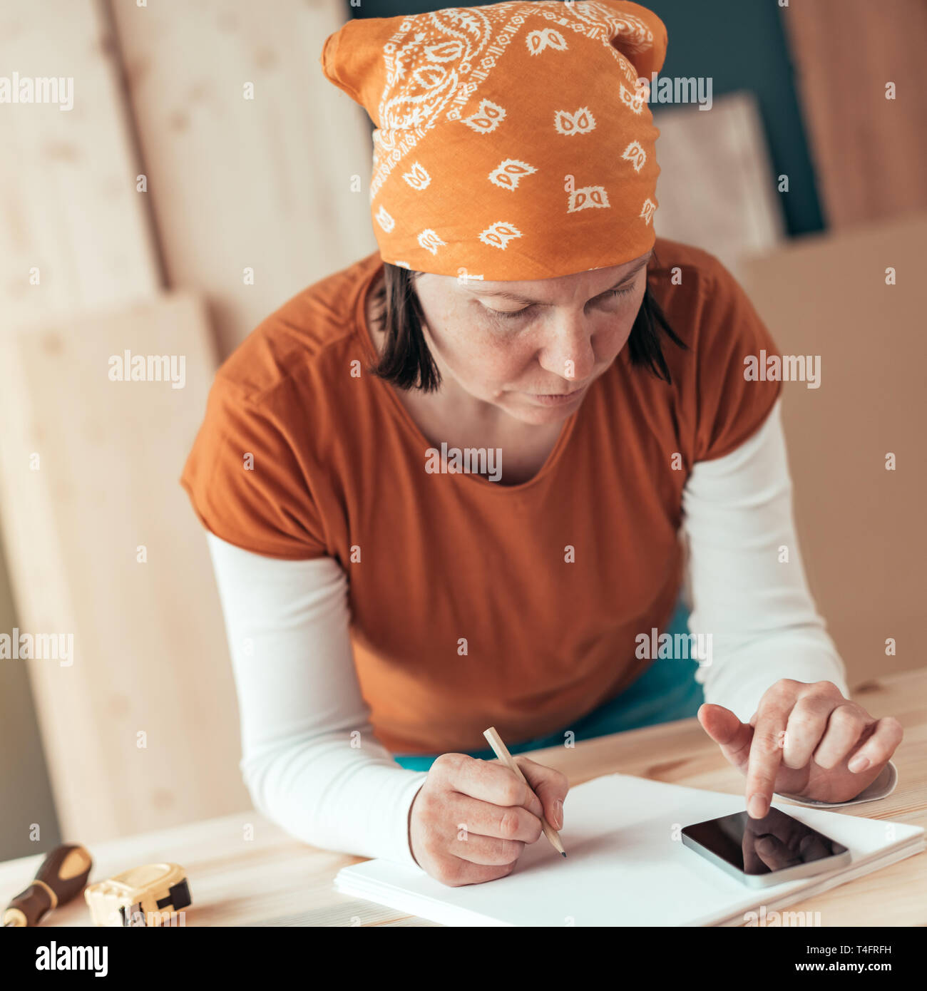 Frau Carpenter mit Kopftuch tun finanzielle Berechnung in der Schreinerei Holzarbeiten workshop Stockfoto