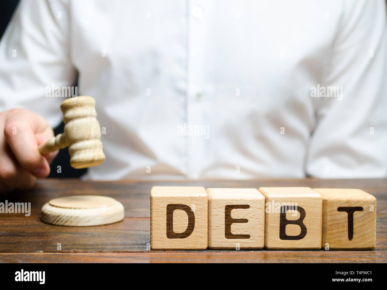 Holzblöcke mit dem Wort Schulden und Richter mit einem Hammer. Das Konzept der gerichtlichen Strafe für nicht-Zahlung von Schulden. Eigentum schulden. Steuerhinterziehung/Avo Stockfoto