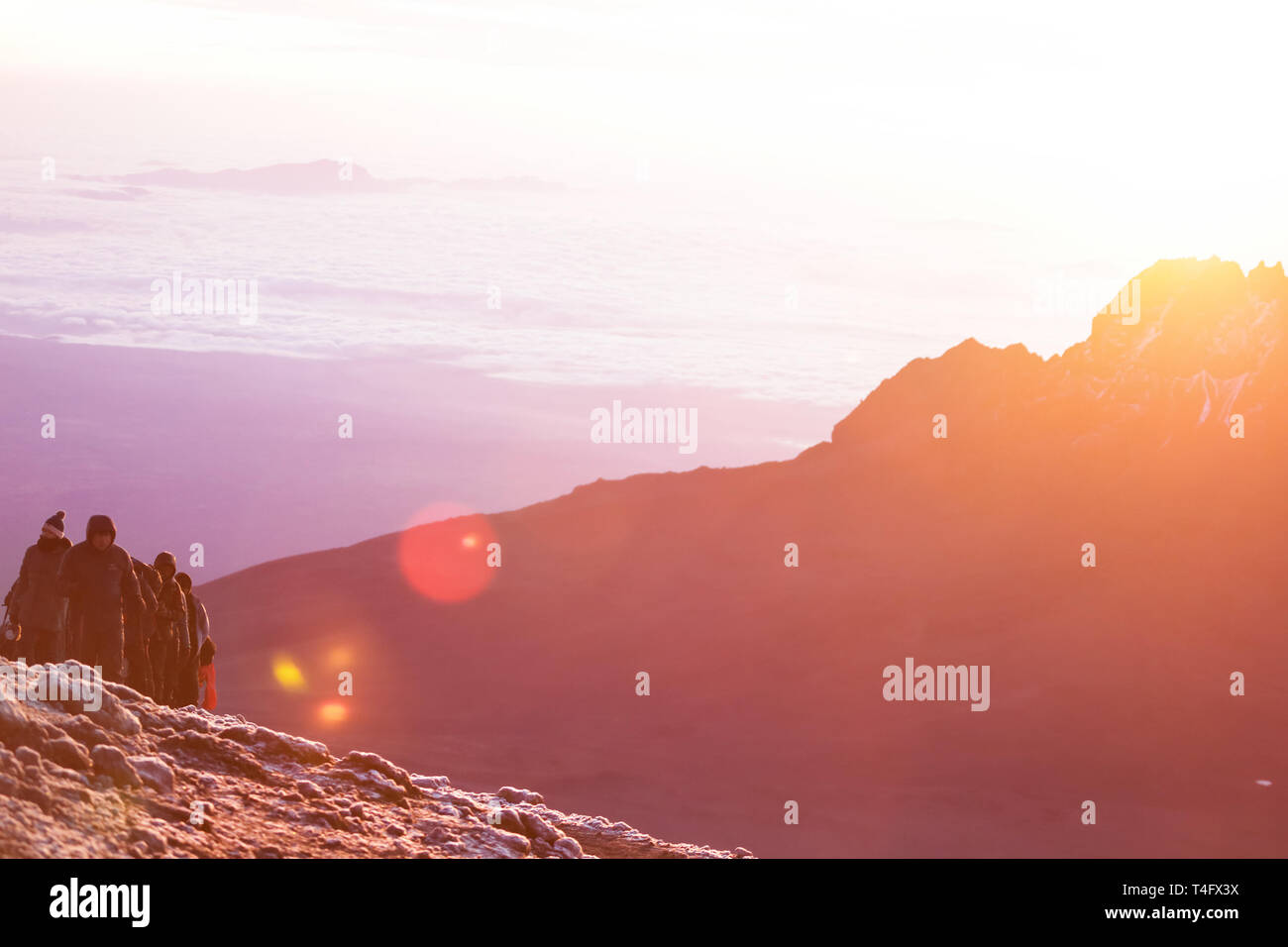 Unglaubliche Natur Schönheit, Sonnenaufgang in den Bergen. Menschen klettern auf den Gipfel. Gelbe warmes Licht und eiskalt auf die 5000 Meter hoch. Stockfoto