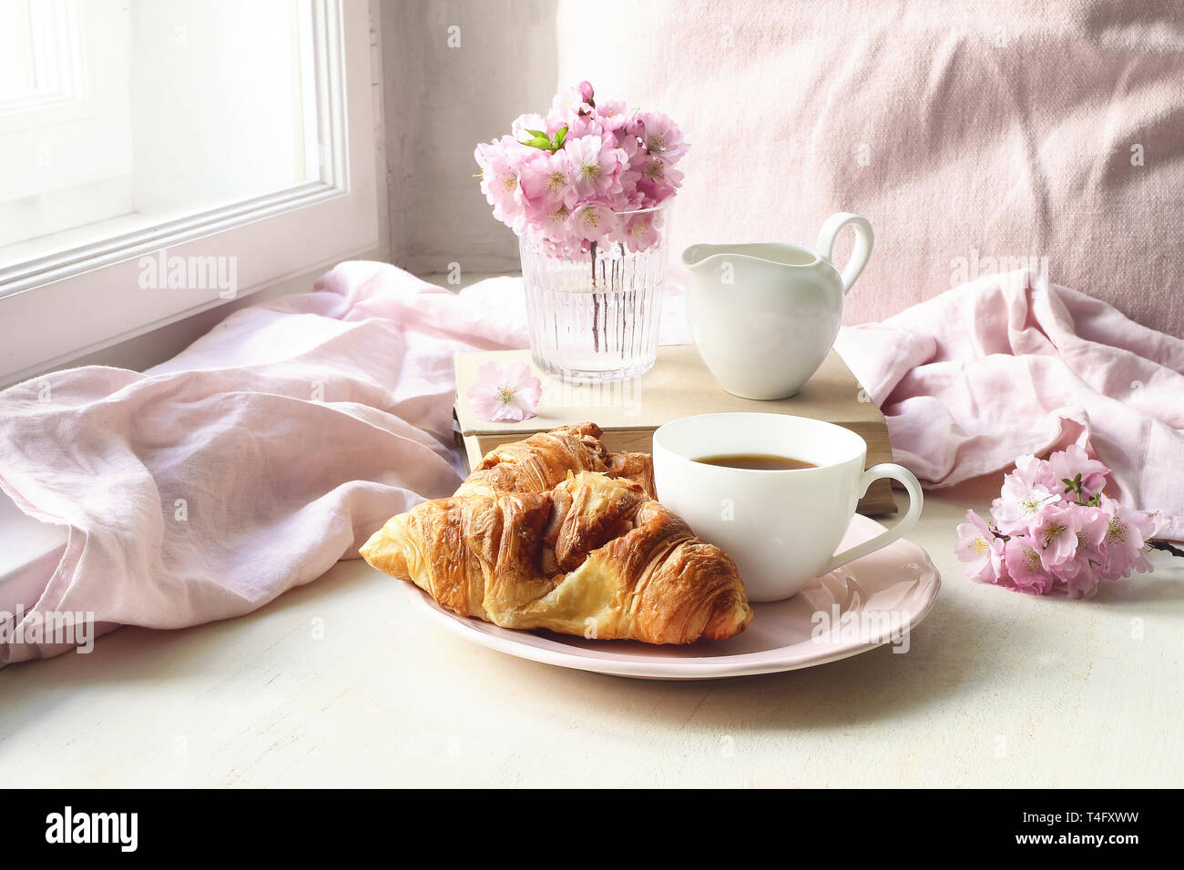 Der Frühling noch leben Szene. Tasse Kaffee, Croissants, Gebäck, alte Bücher und Milch Krug. Vintage feminin Foto, blumige Komposition mit Rosa saku Stockfoto