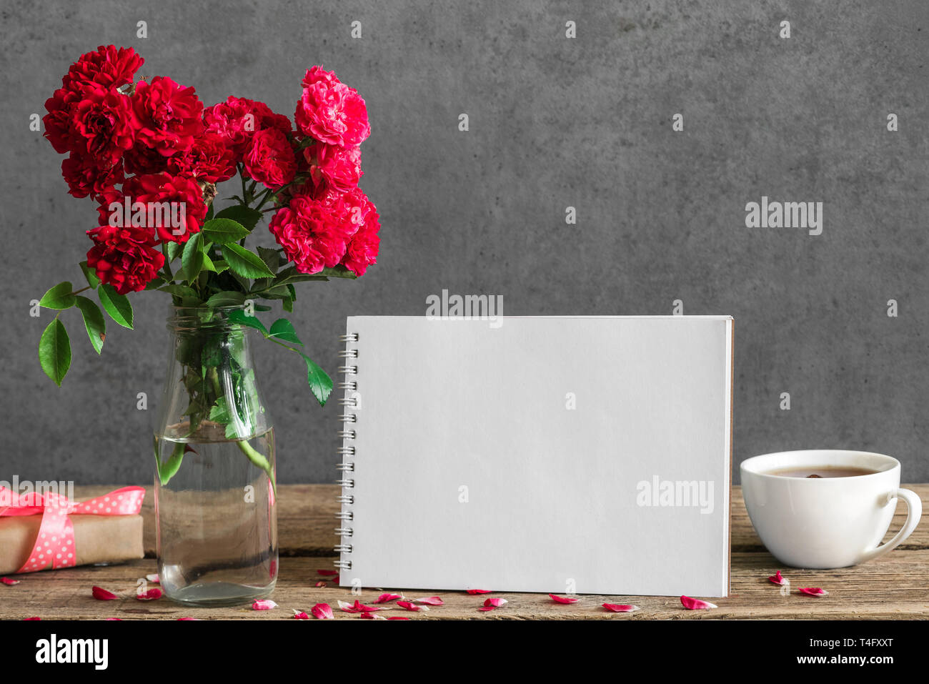 Leere Grußkarte mit Blumenstrauß aus Rosen, Tasse Tee und Geschenkbox. Hochzeit Hintergrund. Mock up Stockfoto