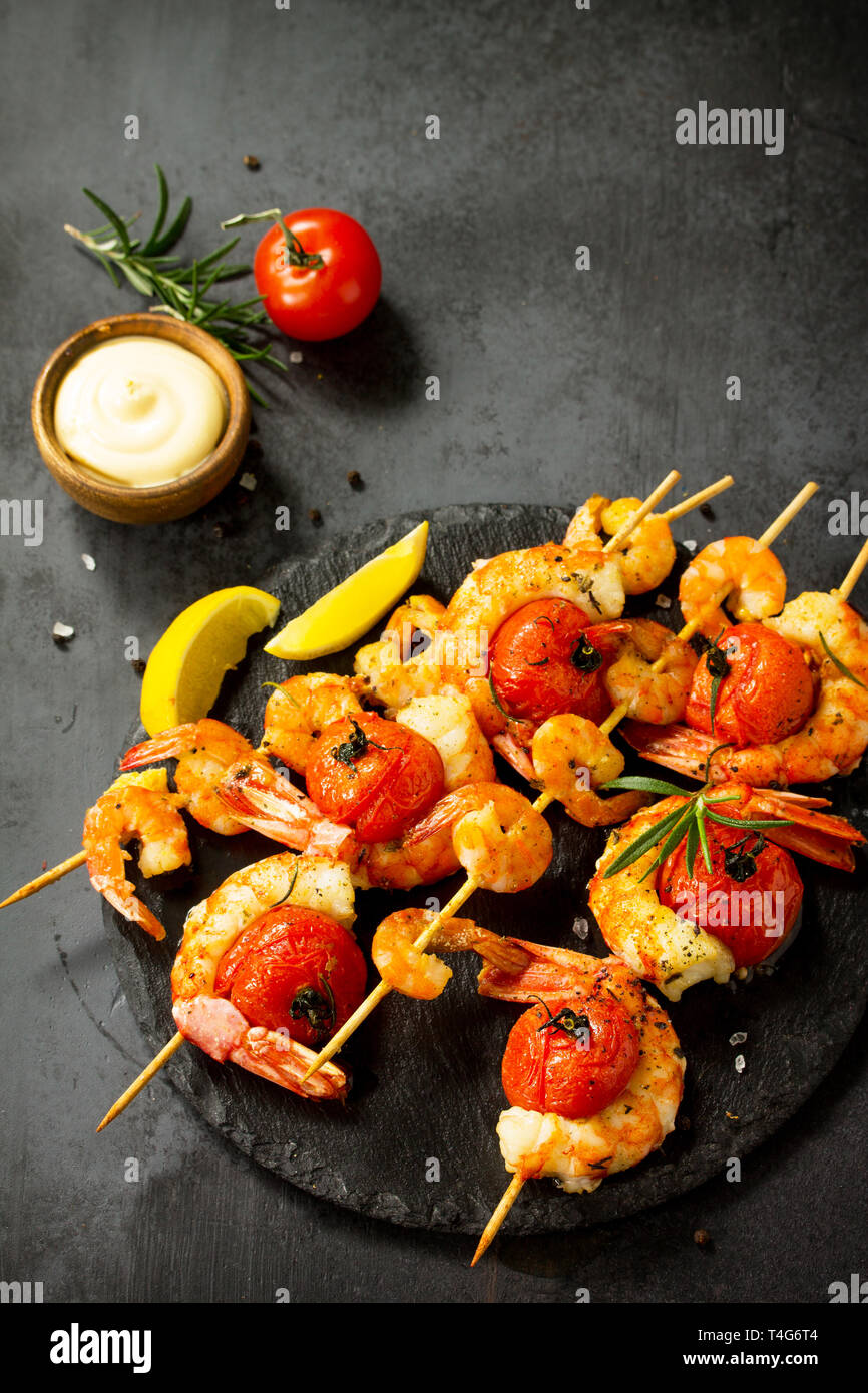 Gegrillte Meeresfrüchte. Köstliche gegrillte Tiger Garnelen mit Tomaten, Zitrone und Soße auf einer Schiefer Board serviert. Fisch und Meeresfrüchte. Kopieren Sie Platz. Stockfoto
