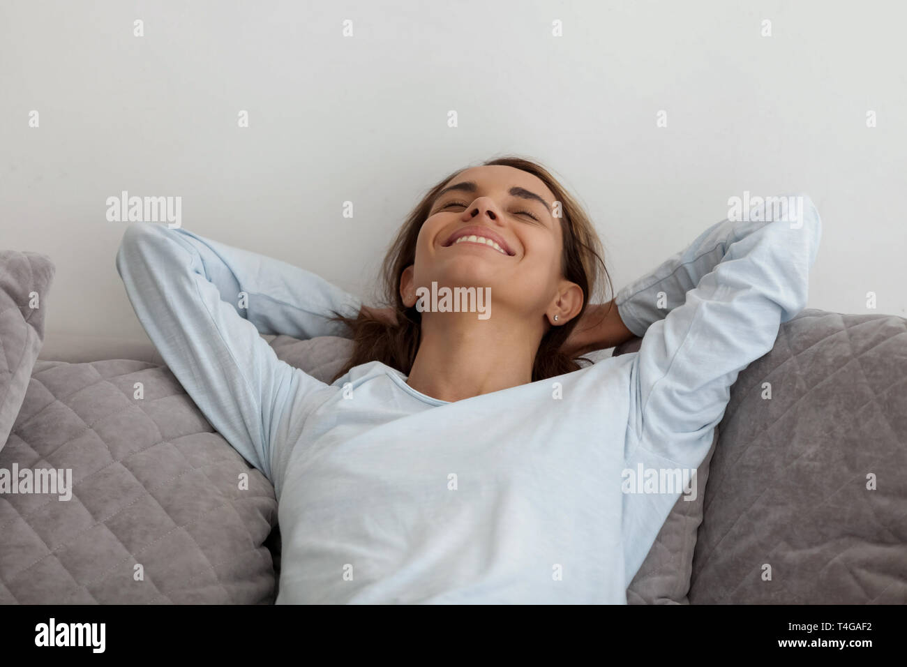 Schöne lächelnde Frau entspannt auf einem Sofa mit geschlossenen Augen Stockfoto