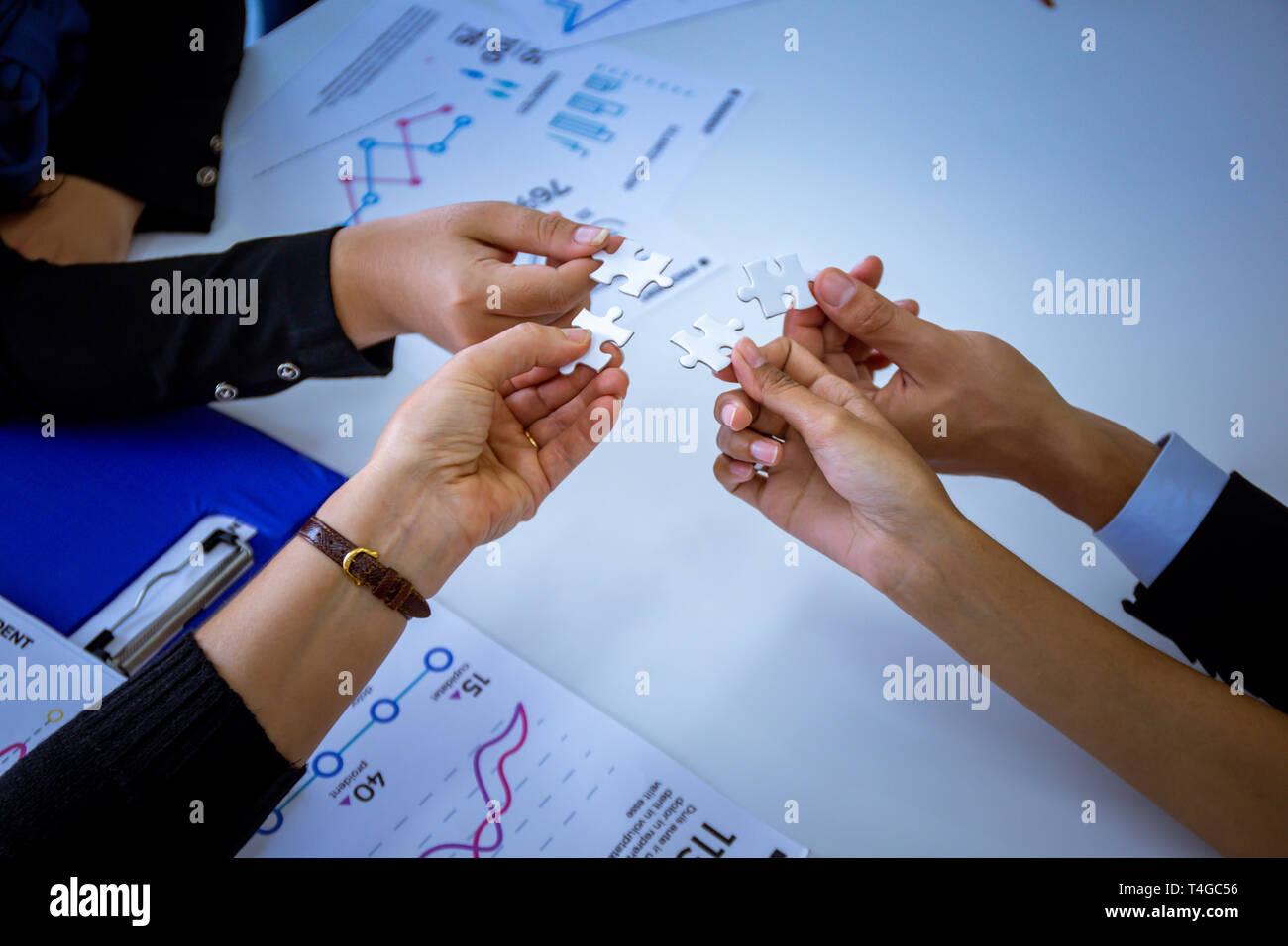 Hände von anonymen Menschen Stücke weiß Puzzle im Büro Stockfoto