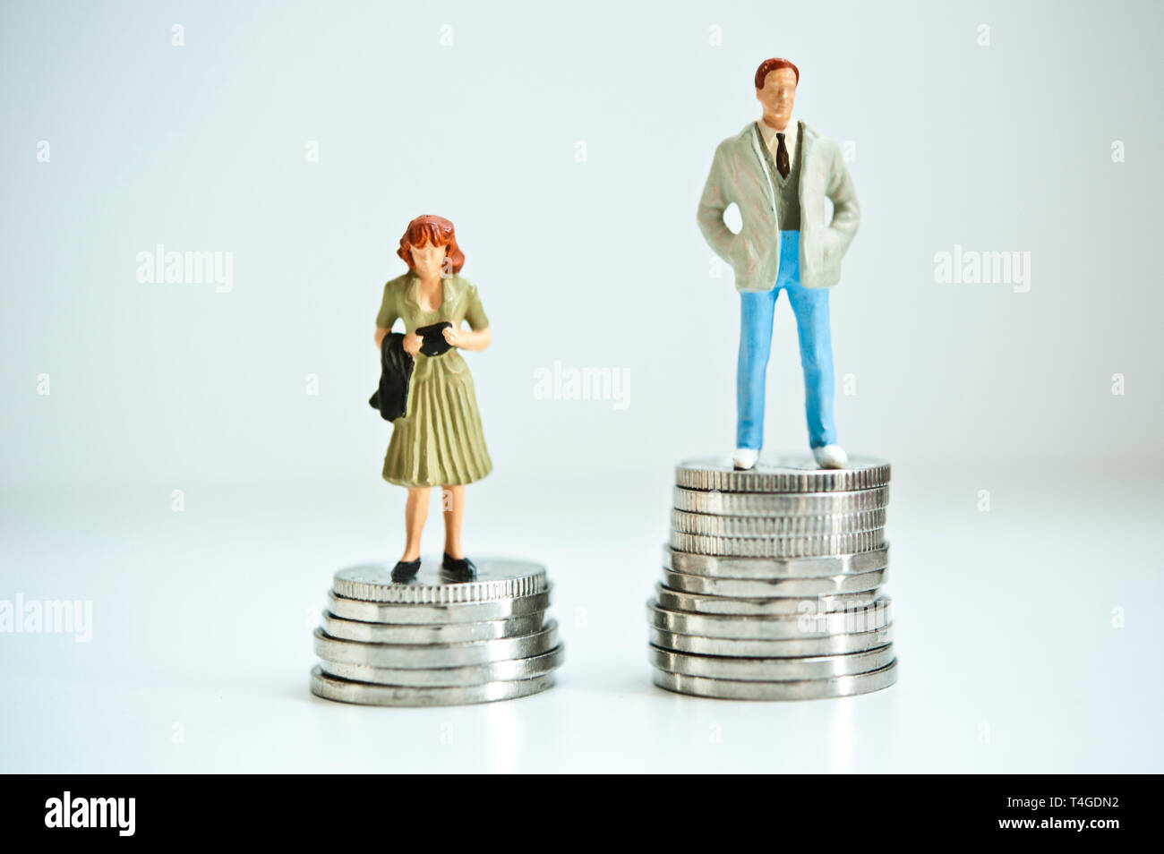 Mann und Frau Figur stehend auf Münzen, Gender Pay Gap Konzept Stockfoto