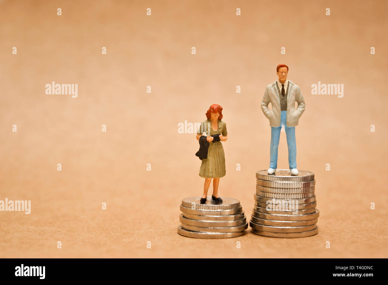 Mann und Frau Figur stehend auf Münzen, Gender Pay Gap Konzept Stockfoto