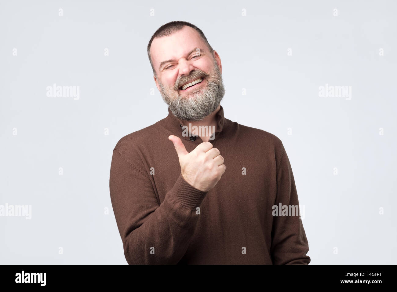Reifen kaukasischen Mann Daumen hoch geben und auf grauem Hintergrund lachen isoliert. Studio gedreht. Positive facial Emotion. Stockfoto
