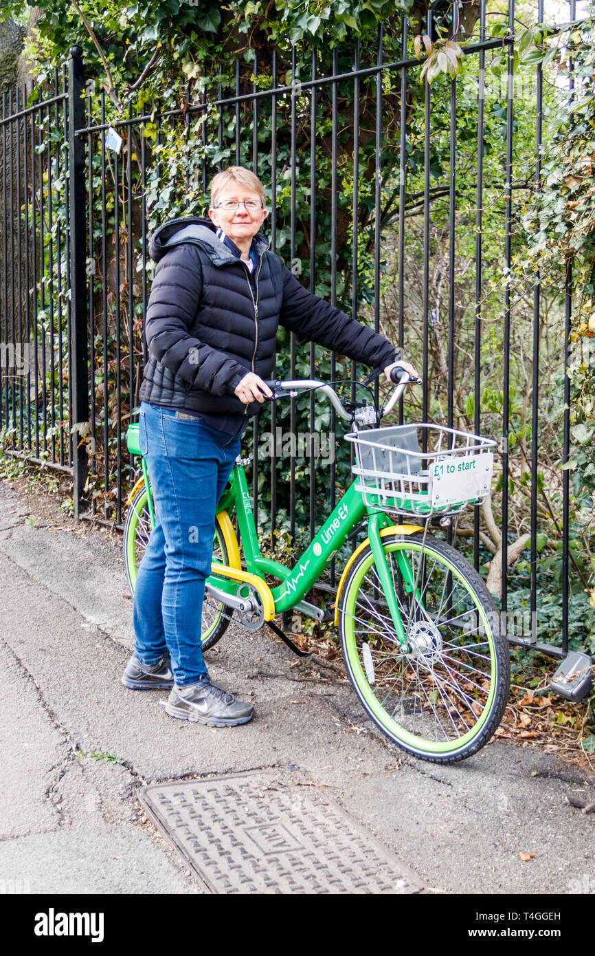 Eine Frau mittleren Alters mit einem Kalk-E dockless Elektrische unterstützen Fahrrad in Highgate, nördlich von London, Großbritannien Stockfoto