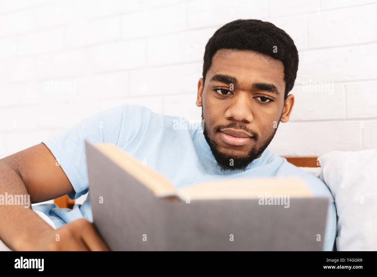Schwarzer Mann Studium der Literatur im Bett Stockfoto
