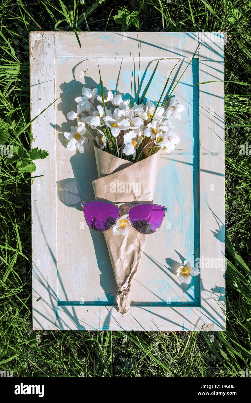 Konzept Sommer kreative Hintergrund Blumenstrauß in Papier und Sonnenbrille auf Holz- Hintergrund gewickelt ist Stockfoto